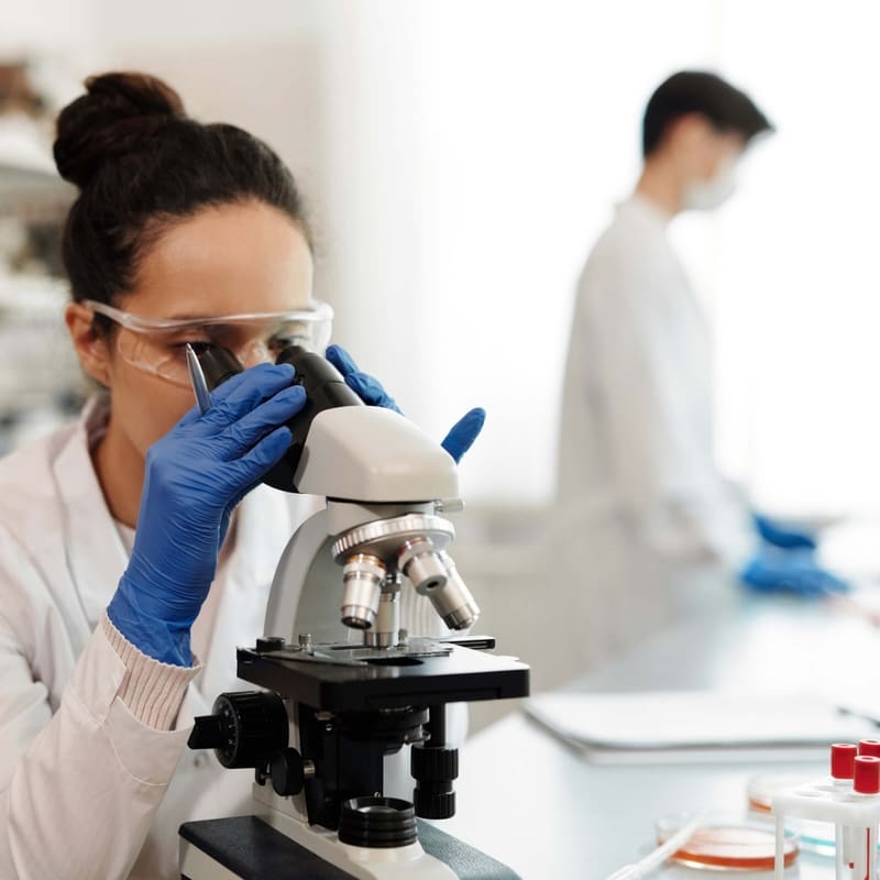 A laboratory scientist reviewing a slide under a microscope